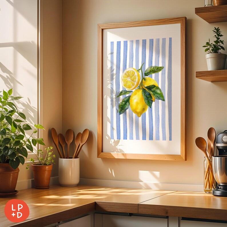 May include: A framed art print featuring a watercolor illustration of lemons with green leaves against a blue and white striped background. The artwork is displayed in a light wood frame, adding a touch of rustic charm to the kitchen setting.