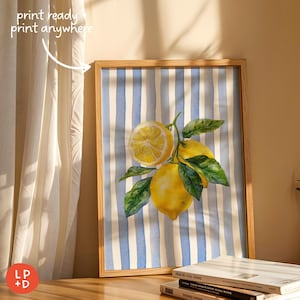 May include: A framed watercolor print featuring a cluster of lemons with green leaves against a blue and white striped background. The print is in a light wood frame. Text in the upper left corner reads "print ready + print anywhere".