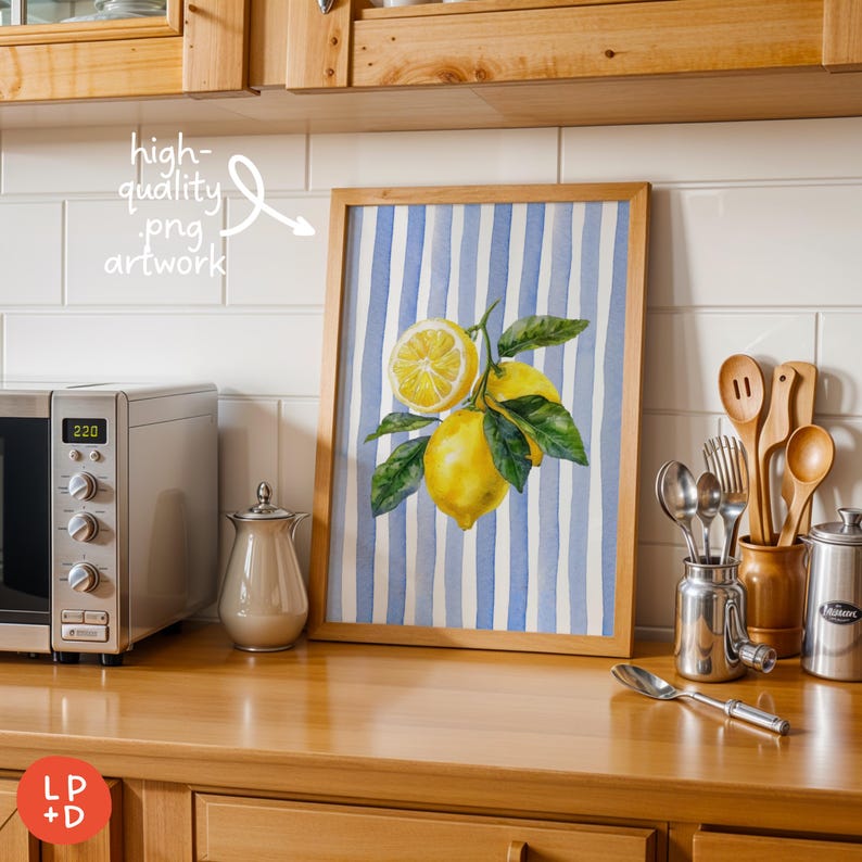 May include: A framed watercolor print featuring lemons and leaves against a blue and white striped background. The artwork is in a wooden frame and is displayed on a wooden countertop. The image also includes a microwave, utensils, and a sugar container.