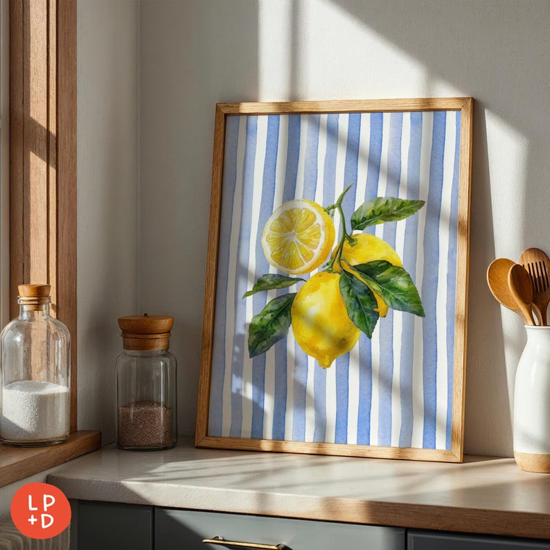 May include: A framed watercolor print featuring a lemon branch with bright yellow lemons and green leaves against a blue and white striped background. The artwork is in a light brown wooden frame.