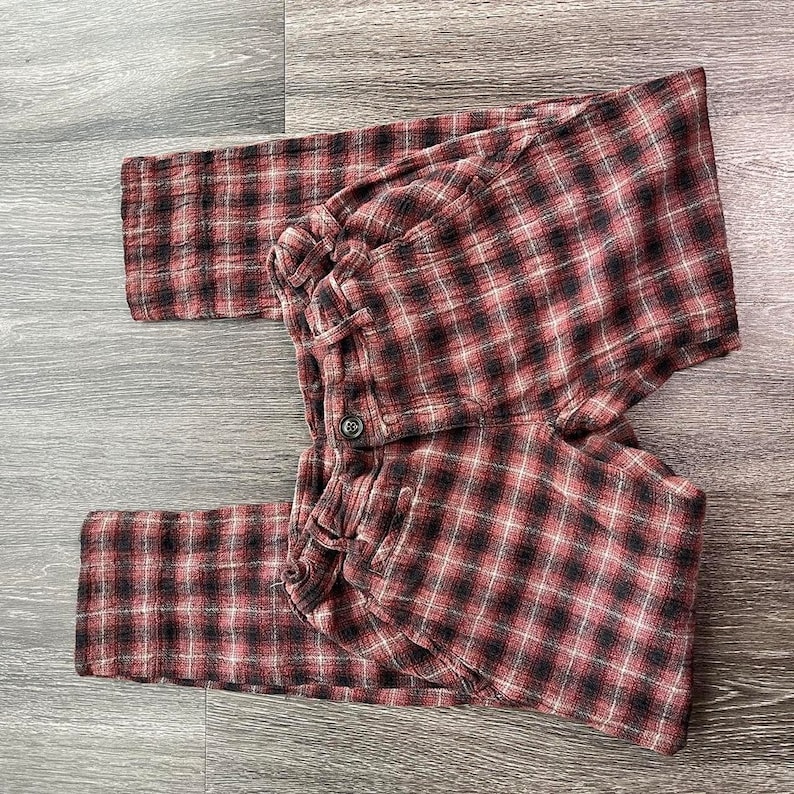 May include: Red and black checked trousers with a button fastening. The trousers are made from a soft, comfortable fabric.