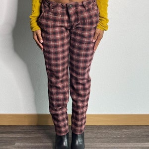 May include: Red and black checked trousers with a relaxed fit. The trousers have a button fly and belt loops.