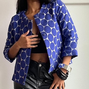 May include: A blue and white polka dot blazer with a button fastening. The blazer has a cropped length and three-quarter sleeves.