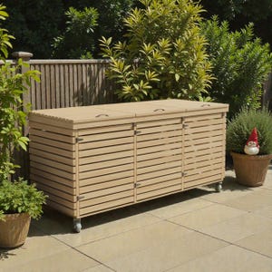 May include: A light-colored wooden outdoor storage cabinet with a slatted design. The cabinet has three doors and two hinged lids with handles. It sits on small wheels and is surrounded by greenery.