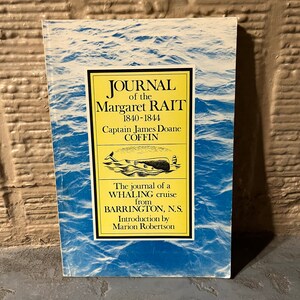 May include: A book titled "Journal of the Margaret Rait 1840-1844" with a blue and white ocean-themed cover. The cover features a yellow rectangle with black text and illustrations of a whale and a lighthouse. The book is about a whaling cruise.