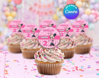 Op de afbeelding: Roze en witte cupcake-toppers met een Minnie Mouse-figuur en de tekst "Amelia wordt 2".