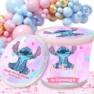 May include: Pink and blue party favor cups with a cartoon Stitch character. The cups have a pink and blue watercolor background with white hearts and butterflies. The text on the cups reads "Thank you for coming to my party" and "Brittany is turning 5".