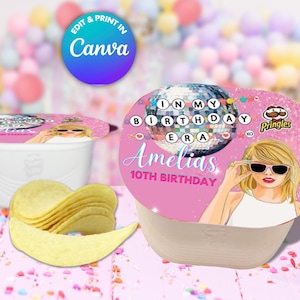Puede incluir: Un vaso de aperitivo Pringles con una tapa personalizada con una bola de discoteca, el texto "IN MY BIRTHDAY ERA" y una ilustración de dibujos animados de una mujer con gafas de sol. La taza es rosa y blanca, con el nombre "Amelias" y "10TH BIRTHDAY" impresos. Un montón de patatas fritas está delante.