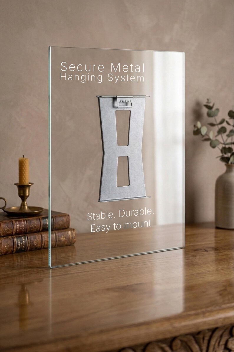 May include: A clear glass panel with a secure metal hanging system. The text on the glass reads "Secure Metal Hanging System" and "Stable. Durable. Easy to mount." The metal bracket is silver. The panel is on a wooden surface.