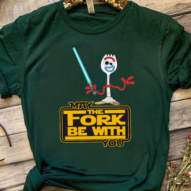 K&ouml;nnte beinhalten: Gr&uuml;nes T-Shirt mit einem Cartoon-Bild einer Gabel, die ein Lichtschwert h&auml;lt. Der Text "M&ouml;ge die Gabel mit dir sein" ist in Gelb auf dem T-Shirt gedruckt.