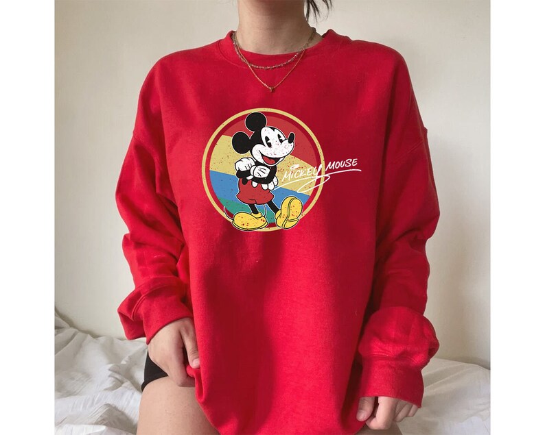 Puede incluir: Sudadera roja con un gr&aacute;fico vintage de Mickey Mouse y el texto "Mickey Mouse" en blanco. El gr&aacute;fico presenta a Mickey Mouse en un c&iacute;rculo amarillo, rojo y azul.