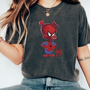 Puede incluir: Una camiseta gris oscuro con una imagen de dibujos animados de un cerdo con un traje de Spiderman rojo y azul. El cerdo est&aacute; de pie con los brazos cruzados y un peque&ntilde;o logotipo de Spiderman debajo.