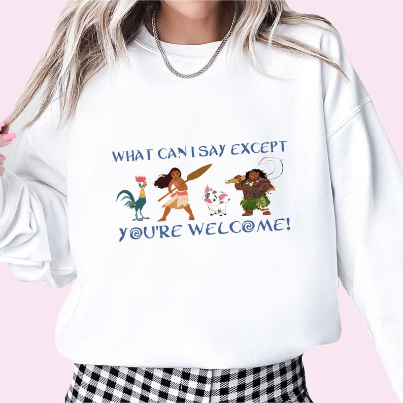 May include: White sweatshirt with a graphic print of characters from the animated movie Moana. The text on the shirt reads "What can I say except you're welcome!"