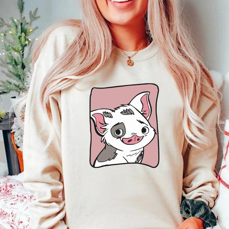 May include: A cream-colored sweatshirt with a cartoon pig illustration. The pig is white with black spots and has a pink nose and ears. The pig is surrounded by a pink square.