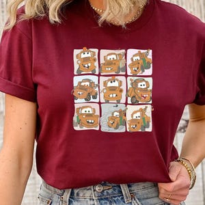 Puede incluir: Camiseta color burdeos con una imagen de dibujos animados de una gr&uacute;a con diferentes expresiones faciales en una cuadr&iacute;cula.