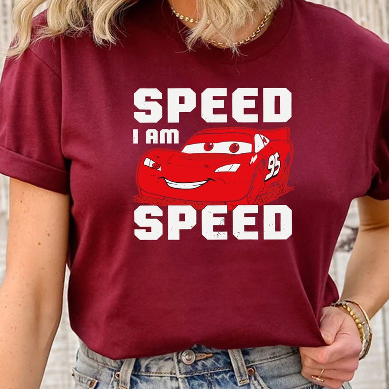 Puede incluir: Una camiseta color granate con un gr&aacute;fico blanco de un coche de carreras rojo con el texto "SPEED I AM SPEED" impreso en ella.