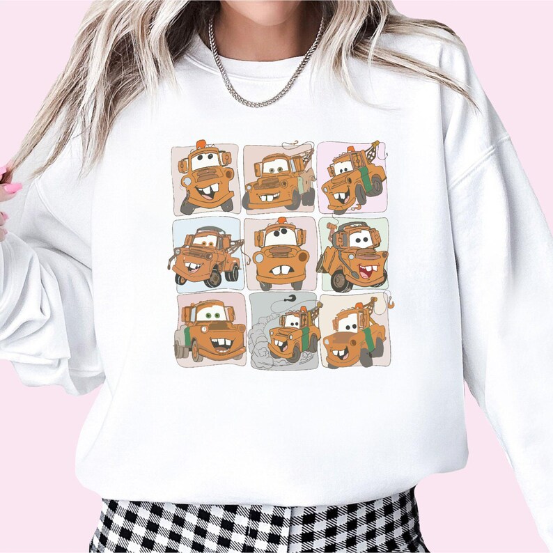Puede incluir: Sudadera blanca con una imagen de dibujos animados de una gr&uacute;a de remolque con diferentes expresiones faciales en un patr&oacute;n de cuadr&iacute;cula.