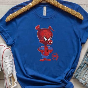 Puede incluir: Una camiseta azul real con una imagen de dibujos animados de un cerdo con un disfraz de Spiderman rojo y azul. El cerdo est&aacute; de pie con los brazos cruzados y tiene una expresi&oacute;n seria en su rostro. Hay una peque&ntilde;a imagen de una telara&ntilde;a en la esquina inferior derecha de la camiseta.