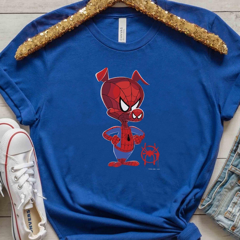 Puede incluir: Una camiseta azul real con una imagen de dibujos animados de un cerdo con un disfraz de Spiderman rojo y azul. El cerdo est&aacute; de pie con los brazos cruzados y tiene una expresi&oacute;n seria en su rostro. Hay una peque&ntilde;a imagen de una telara&ntilde;a en la esquina inferior derecha de la camiseta.