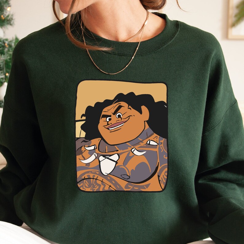 May include: A dark green sweatshirt featuring a cartoon image of a Polynesian man with a large smile and tattoos. The man is wearing a lei and has a brown background.