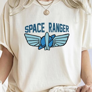 May include: A white t-shirt with a blue and black graphic of a rocket ship with wings and the text "SPACE RANGER".
