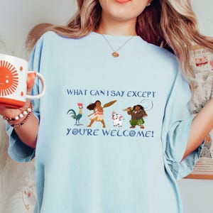 May include: Light blue t-shirt with a graphic of characters from the animated film Moana. The text "What can I say except you're welcome!" is printed on the shirt.