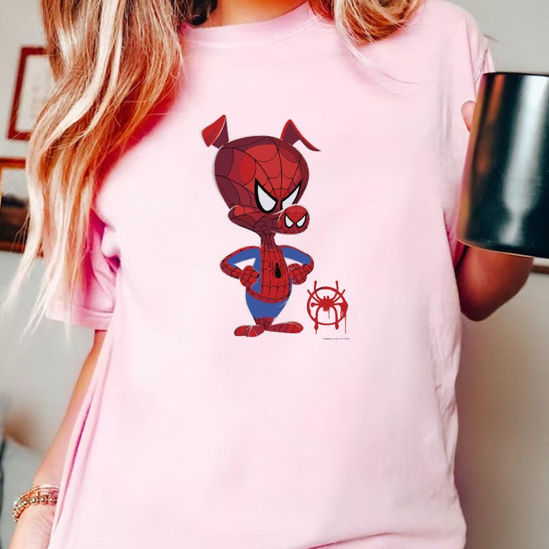 Puede incluir: Camiseta rosa con una imagen de dibujos animados de un cerdo con un traje de Spider-Man rojo y azul. El cerdo est&aacute; de pie con los brazos cruzados y un s&iacute;mbolo de Spider-Man rojo y negro est&aacute; en el suelo frente a &eacute;l.