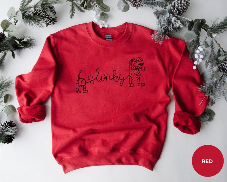 May include: Red sweatshirt with a black outline of Slinky Dog from Toy Story. The text "Slinky" is written in a cursive font.