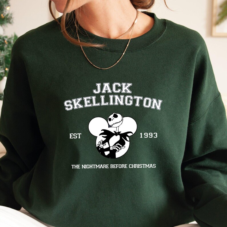 May include: Green sweatshirt with a white graphic of Jack Skellington from The Nightmare Before Christmas. The graphic includes the text "Jack Skellington", "Est. 1993", and "The Nightmare Before Christmas".