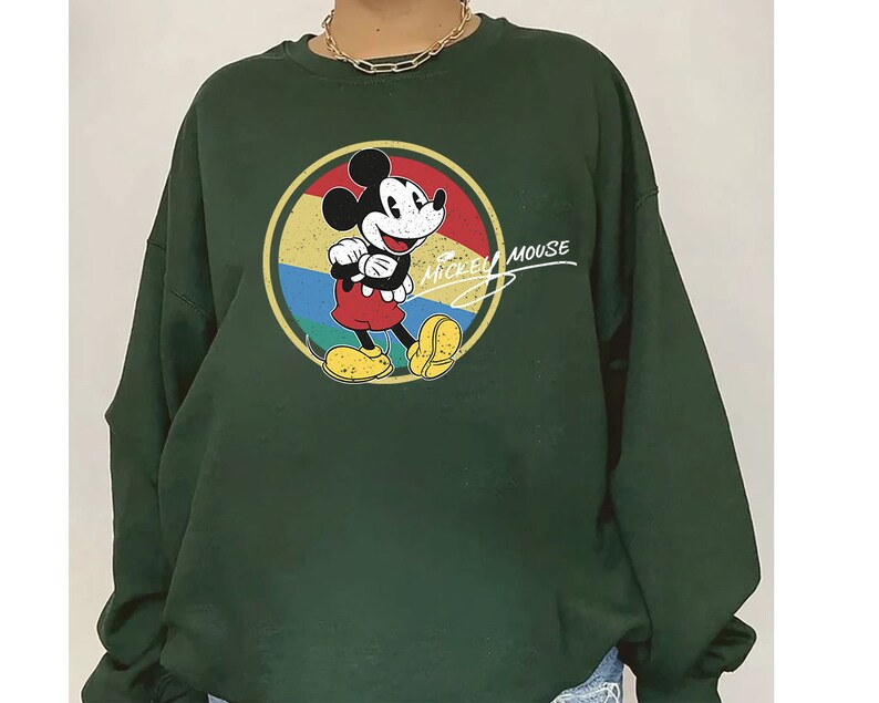 Puede incluir: Una sudadera verde oscuro con un gr&aacute;fico vintage de Mickey Mouse en un c&iacute;rculo colorido. El texto "Mickey Mouse" est&aacute; escrito en cursiva blanca sobre el gr&aacute;fico.