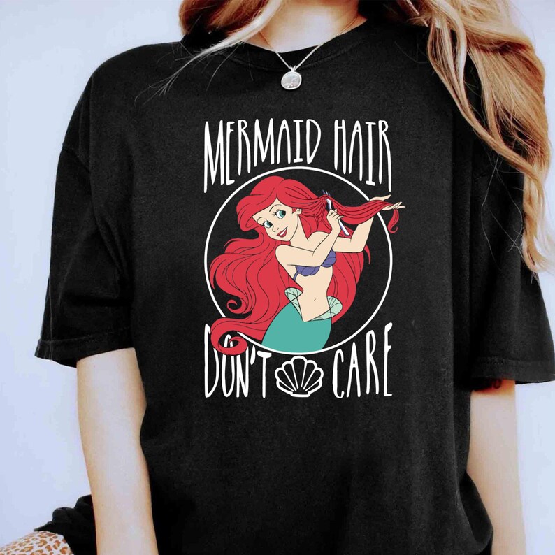 May include: Black t-shirt with a graphic of Ariel from The Little Mermaid brushing her hair. The text "Mermaid Hair Don't Care" is printed on the shirt.