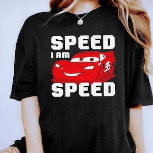 Puede incluir: Camiseta negra con un coche de carreras rojo de dibujos animados y el texto "SPEED I AM SPEED" en blanco.