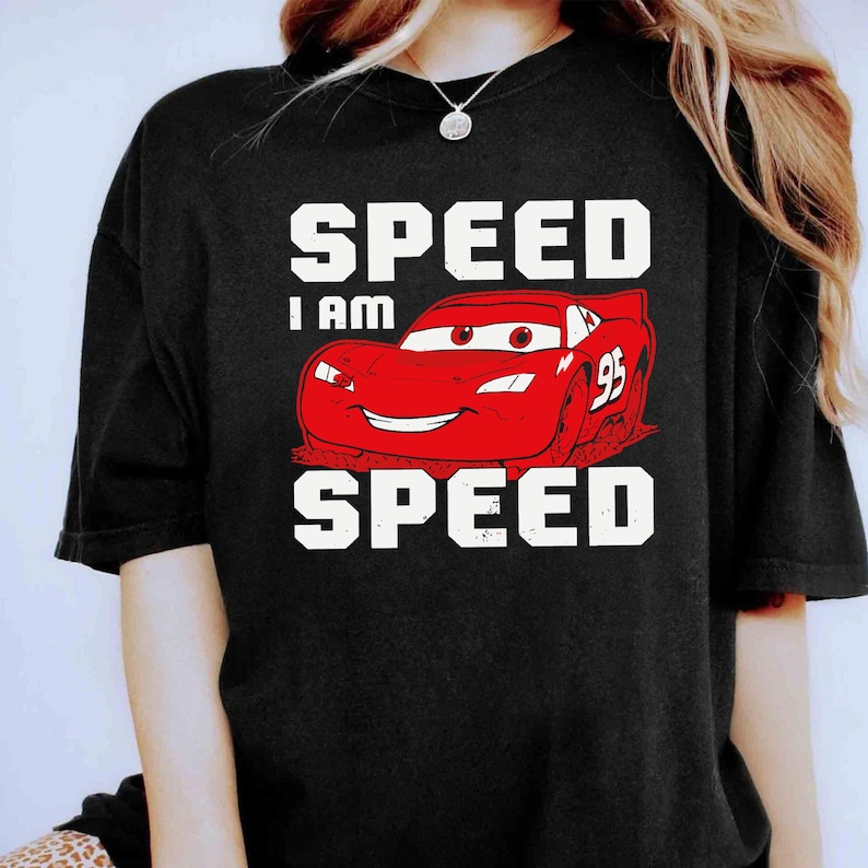 Puede incluir: Camiseta negra con un coche de carreras rojo de dibujos animados y el texto "SPEED I AM SPEED" en blanco.