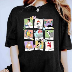 May include: Black t-shirt with a grid of cartoon character portraits from The Little Mermaid. Characters include Eric, Scuttle, Ursula, Flounder, Ariel, Max, King Triton, Melody, and Sebastian. Each portrait is in a polaroid-style frame.