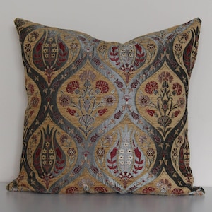May include: A decorative throw pillow with a traditional Turkish design featuring a repeating pattern of stylized tulips, leaves, and flowers in shades of gold, red, blue, and green.