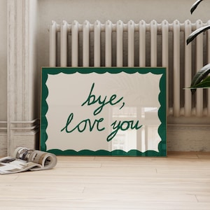 May include: A rectangular framed print featuring a cream-coloured background with a dark green scalloped border. The text "bye, love you" is written in a dark green, cursive, handwritten-style font centred within the frame.