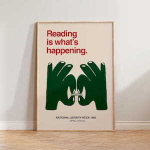 May include: A framed poster with the text "Reading is what's happening" in red. Below, two green hands form a circle around a book. The poster is for National Library Week 1965, April 16 to 22.