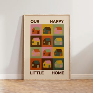 Könnte beinhalten: Gerahmter Kunstdruck mit einem Raster aus bunten Häusern auf cremefarbenem Hintergrund. Die Häuser sind in verschiedenen Farben gehalten, darunter Rosa, Grün, Gelb und Braun. Der Text "OUR HAPPY LITTLE HOME" ist in Braun gedruckt.