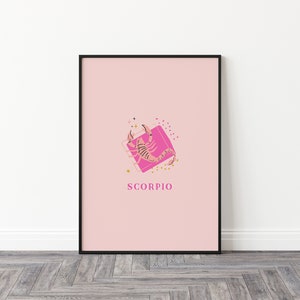 May include: A framed wall art print featuring a light pink background with a central graphic of a scorpion in shades of brown and black. The scorpion is positioned over a bright pink square with gold star and dot accents. The text SCORPIO is below.