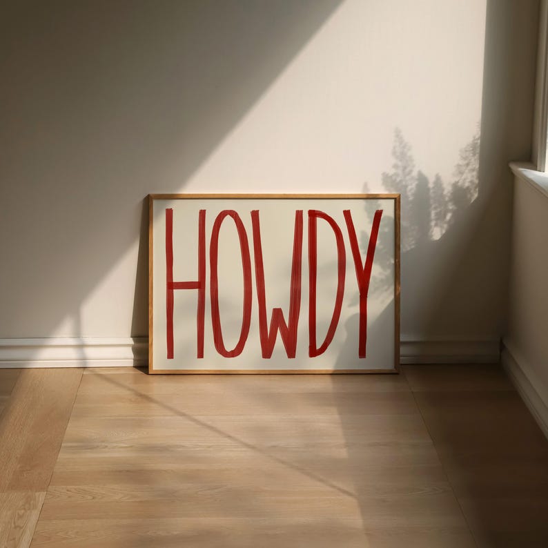Puede incluir: Una impresi&oacute;n enmarcada con la palabra "HOWDY" escrita en rojo sobre un fondo blanco.