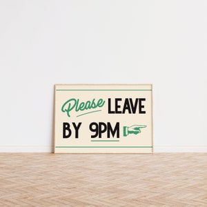 May include: A framed sign with the words "Please Leave By 9PM" in a retro font. The text is in black and green on a cream background, with a pointing hand graphic. The frame is a light wood color.