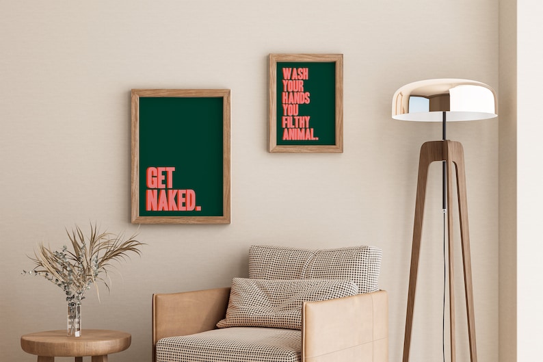 May include: Two rectangular wall art prints in light wood frames. The larger print features the text GET NAKED in coral pink on a dark green background. The smaller print features the text WASH YOUR HANDS YOU FILTHY ANIMAL in coral pink on dark green.