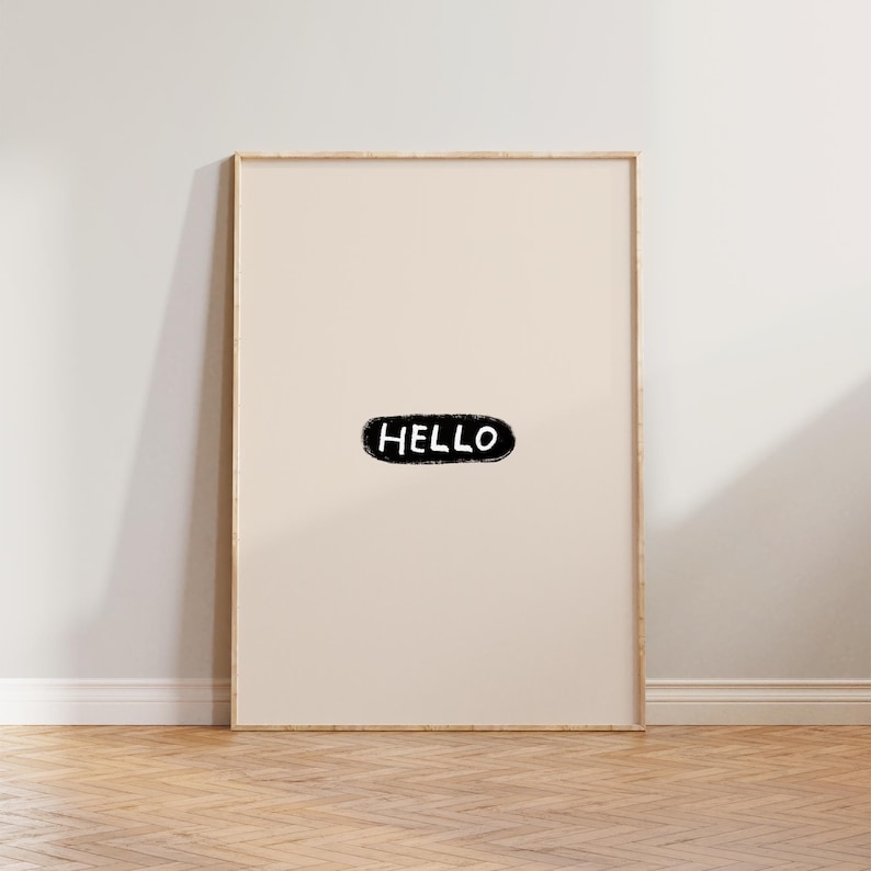 Puede incluir: Una impresi&oacute;n art&iacute;stica enmarcada con la palabra "HELLO" en negro, con textura, sobre un fondo beige claro. El marco es de color madera natural y la obra de arte se exhibe en una pared con suelo de madera.