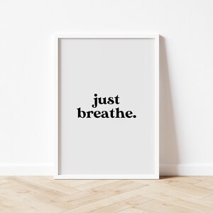 May include: White framed print with the text "just breathe." on a light gray background.