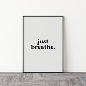 May include: Black framed poster with white background and the text "just breathe." in black bold font.