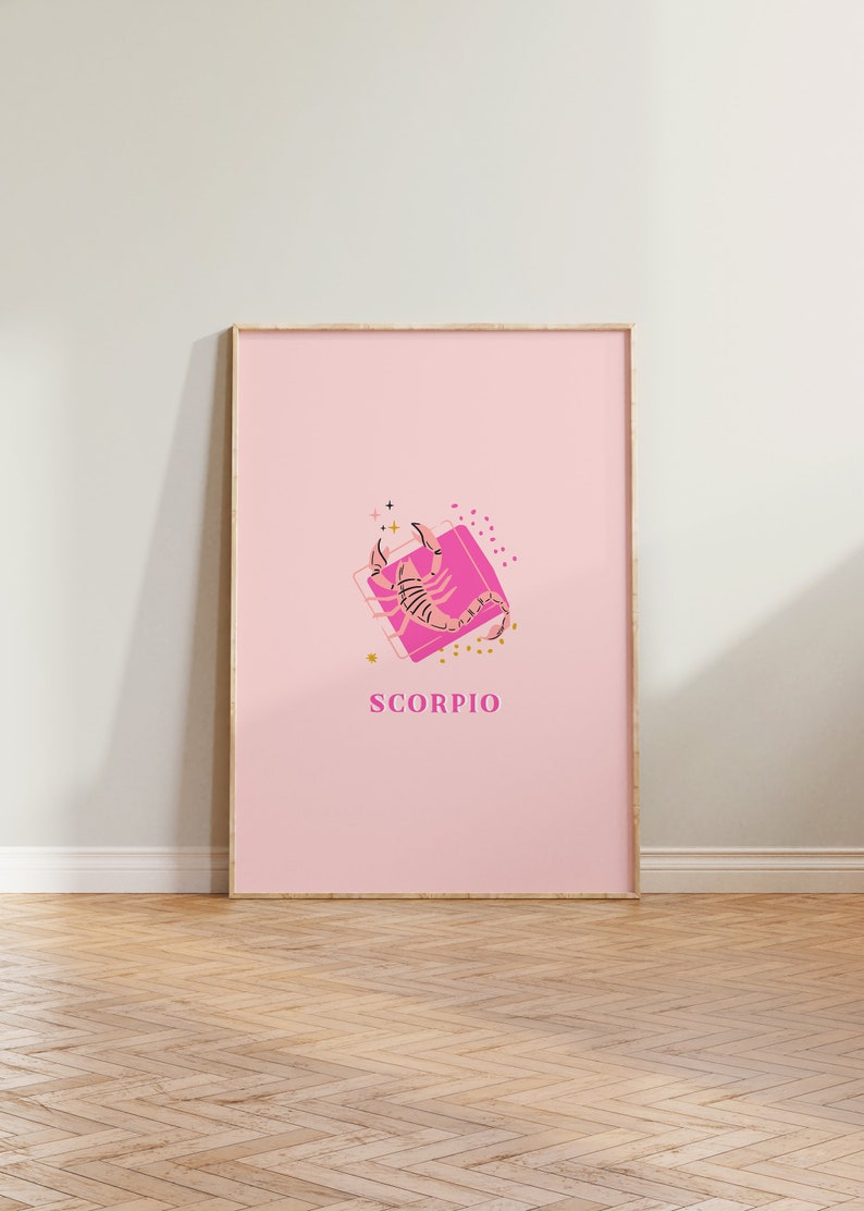 May include: A framed vertical wall art print featuring a light pink background with a central illustration of a scorpion on a bright pink square. The design includes small gold stars and dots, with the word SCORPIO printed in pink capital letters.