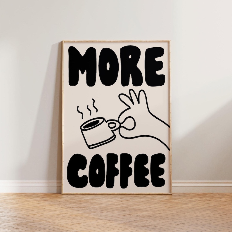 May include: Black and white illustration of a hand holding a steaming cup of coffee with the text "MORE COFFEE" in bold, block letters.