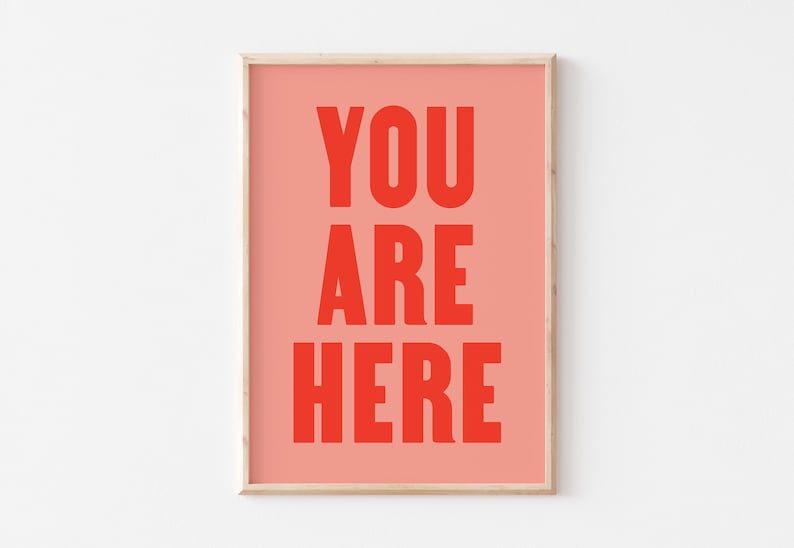 Peut inclure: Une impression encadr&eacute;e avec un fond rose et le texte "YOU ARE HERE" en rouge.