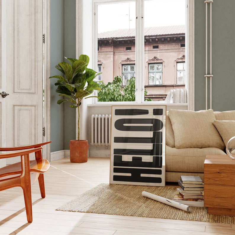 May include: A living room interior with a beige couch, a wooden side table, and a framed print with the word "HELLO" in black letters on a white background.