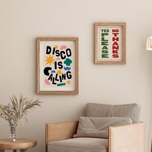 May include: Two framed prints with colorful abstract designs. The print on the left says "Disco is Calling" in black letters with colorful shapes and stars. The print on the right says "Yes Please" in green letters and "No Thanks" in red letters.